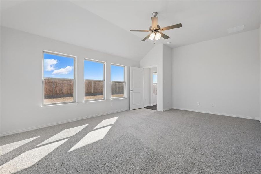 Unfurnished room with light carpet, ceiling fan, and vaulted ceiling