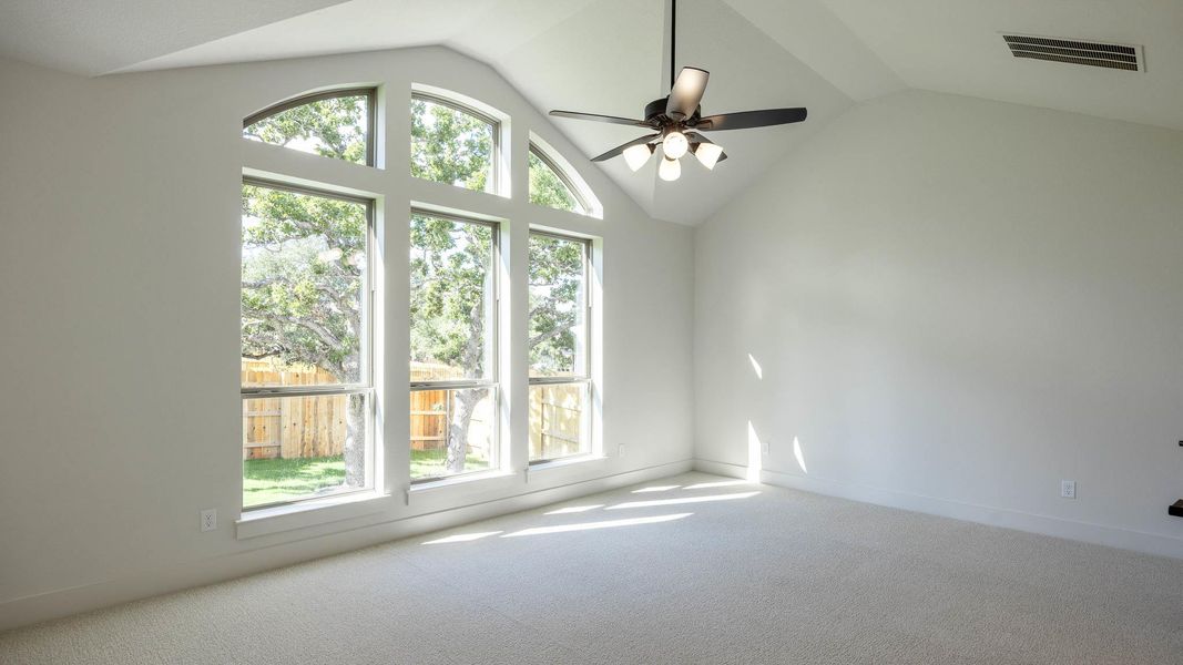 Empty room with vaulted ceiling, carpet floors, and ceiling fan