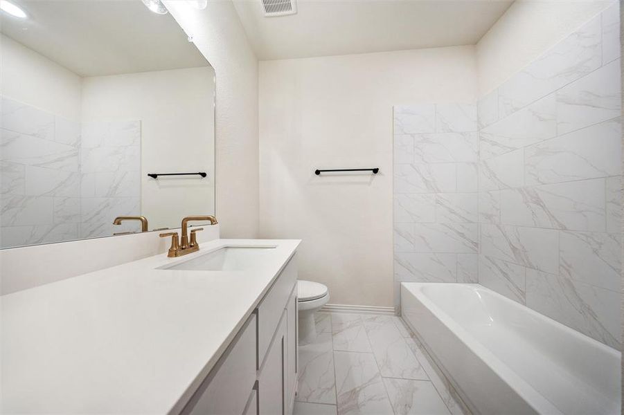 Bathroom featuring vanity, light marble finish floors, and shower / washtub combination