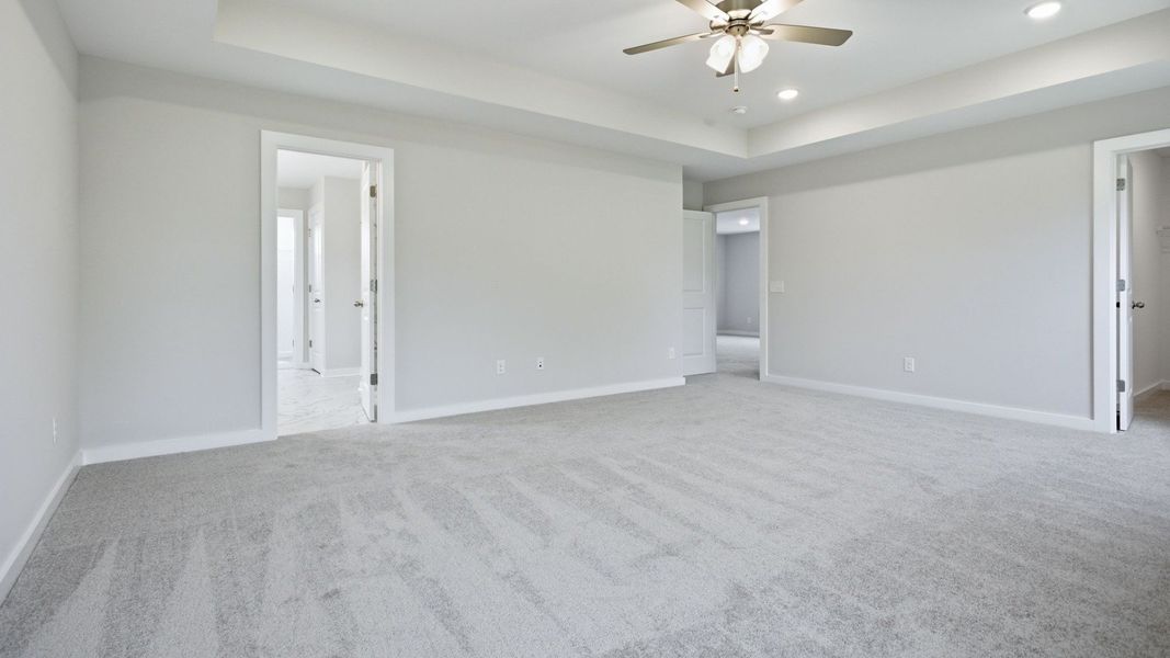 Bedroom with tray ceiling, ceiling fan, and access to primary bathroom, closet, and loft area Bedroom with tray ceiling, ceiling fan, and access to primary bathroom, closet, and loft area