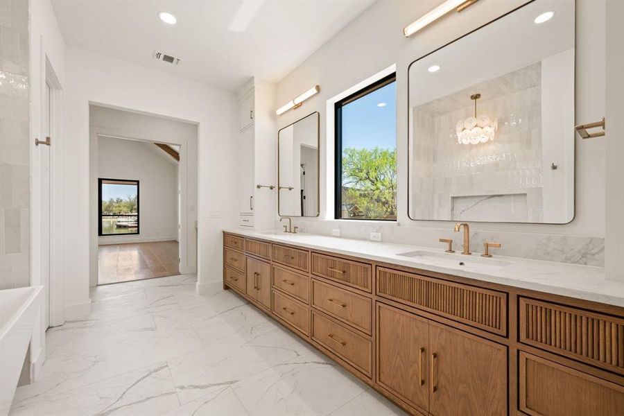 Full bath with marble finish floors, double vanity, a tub, a chandelier, and recessed lighting
