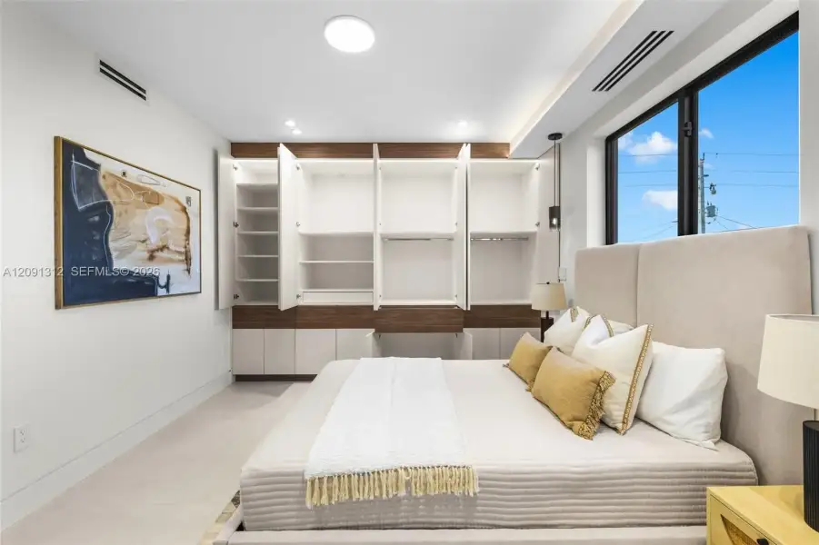Built-in storage wall with two-tone cabinetry, recessed LED lighting, and large window with black frames Built-in storage wall with two-tone cabinetry, recessed LED lighting, and large window with black frames