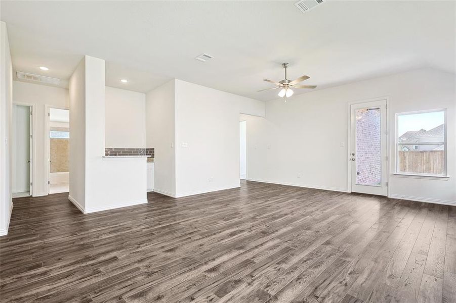 Unfurnished living room featuring ceiling fan and dark hardwood / wood-style flooring