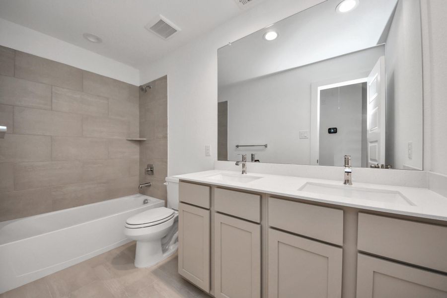 Secondary bath features tile flooring, bath/shower combo with tile surround, light stained wood cabinets, beautiful light countertop. Secondary bath features tile flooring, bath/shower combo with tile surround, light stained wood cabinets, beautiful light countertop.