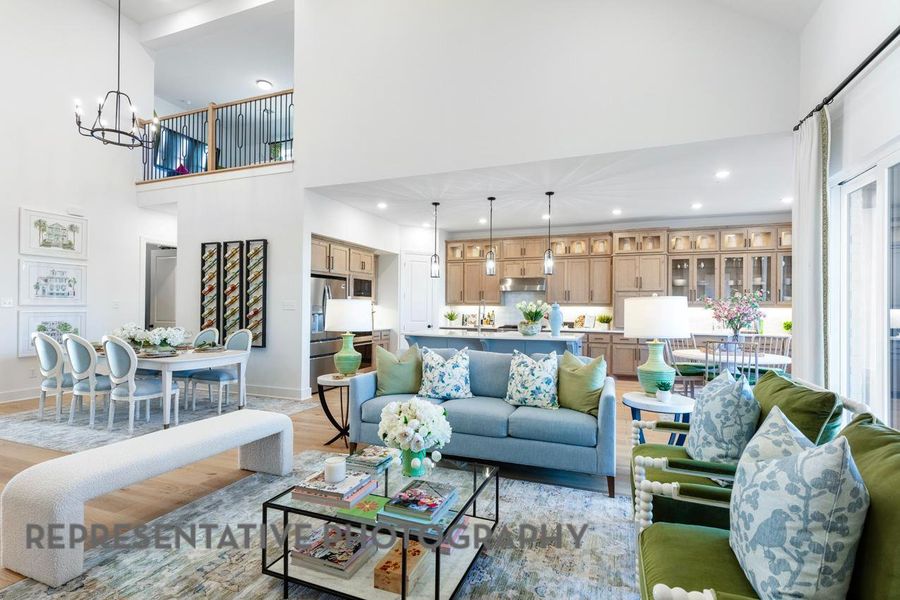 Living area featuring a high ceiling, a chandelier, light wood-type flooring, and recessed lighting Living area featuring a high ceiling, a chandelier, light wood-type flooring, and recessed lighting