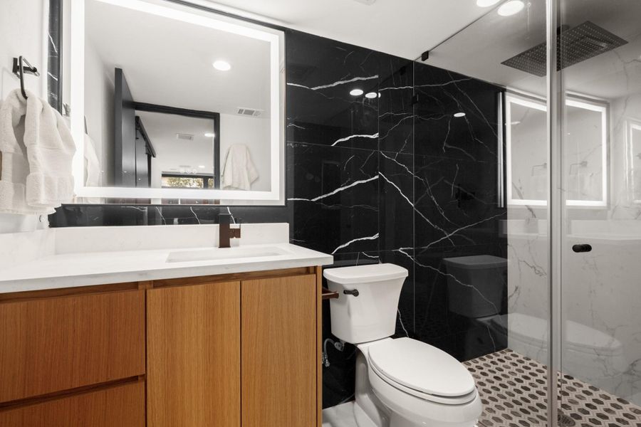 Full bathroom featuring tile walls, vanity, and a marble finish shower