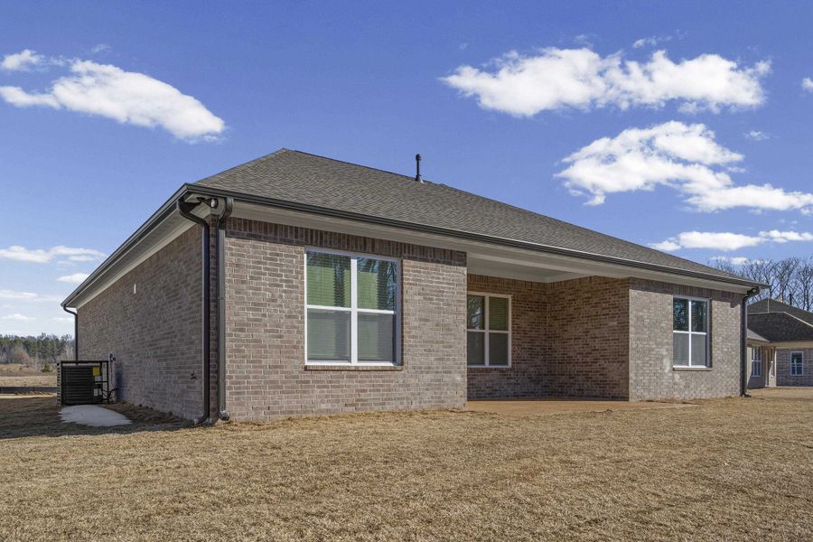 View of property exterior with brick siding, a patio area, and a yard