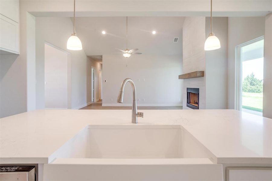 Kitchen with light hardwood / wood-style flooring, decorative light fixtures, a large fireplace, sink, and ceiling fan