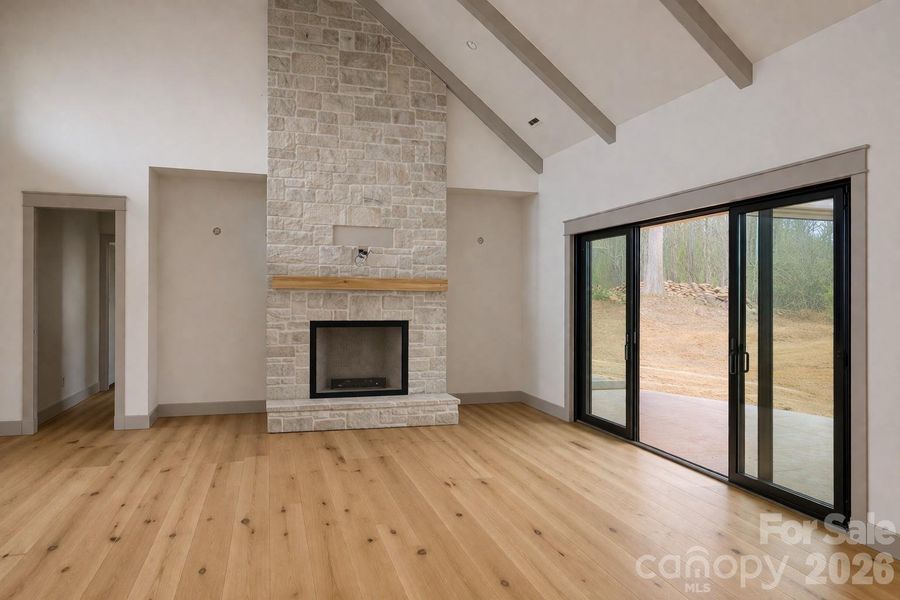 Greatroom showcasing a floor-to-ceiling stone fireplace and impressive 20-foot ceiling height, with sliding glass doors opening to the private outdoor deck.