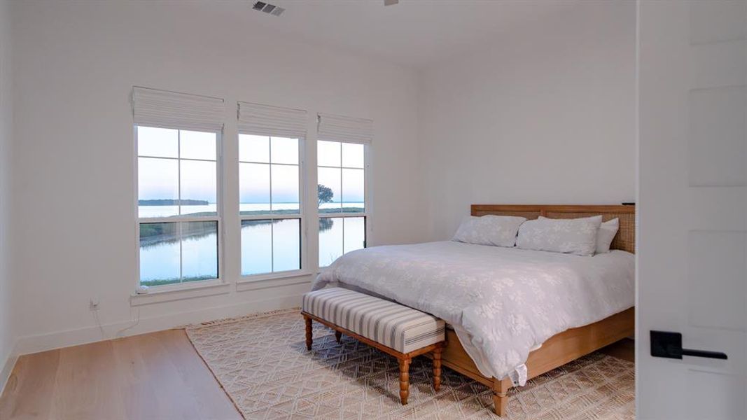 Bedroom featuring a water view, light wood-type flooring, and a ceiling fan Bedroom featuring a water view, light wood-type flooring, and a ceiling fan