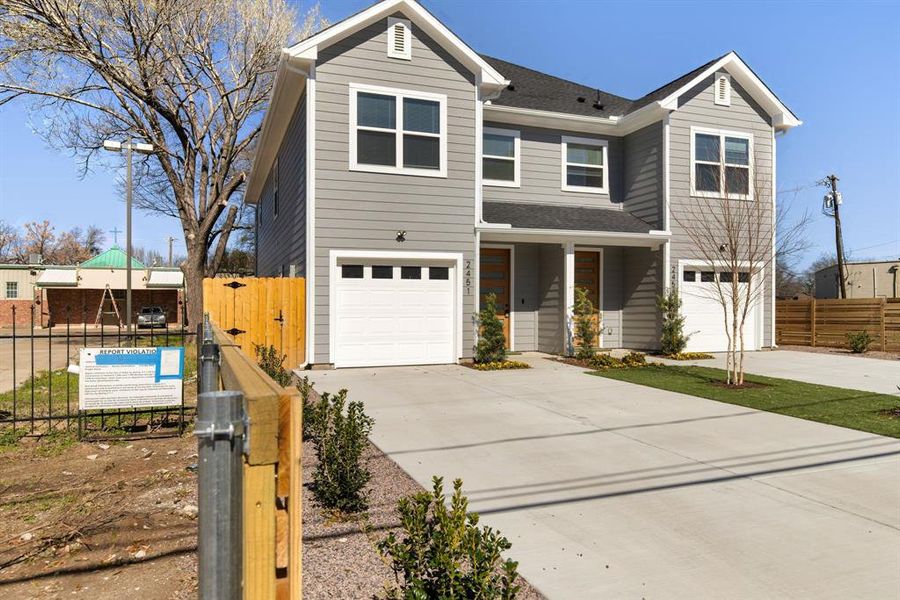 Traditional-style house featuring an attached garage, driveway, and fence