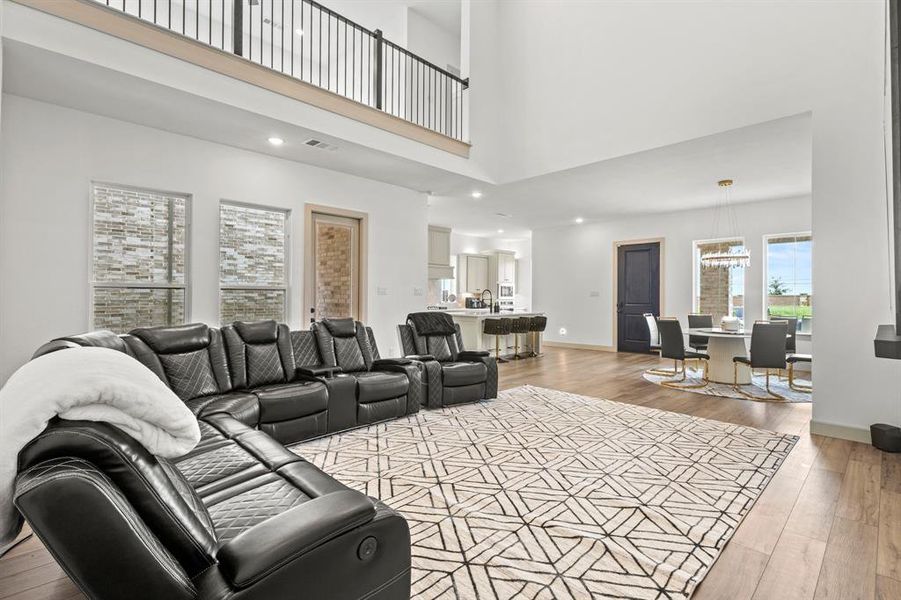 Living room with light wood-type flooring, recessed lighting, a towering ceiling, and a chandelier
