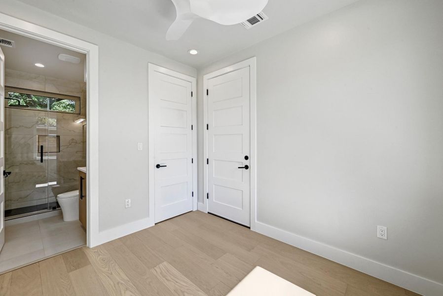 1st Floor Secondary Bedroom with connected bathroom, ceiling fan, and recessed lighting. (This is Unit #2 - each Unit has the same layout, however a few differing details such as light fixtures, custom cabinet/backsplash/tile colors)