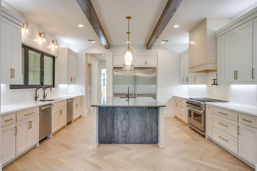Kitchen with high end appliances, decorative light fixtures, parquet floors, light stone countertops, and beam ceiling
