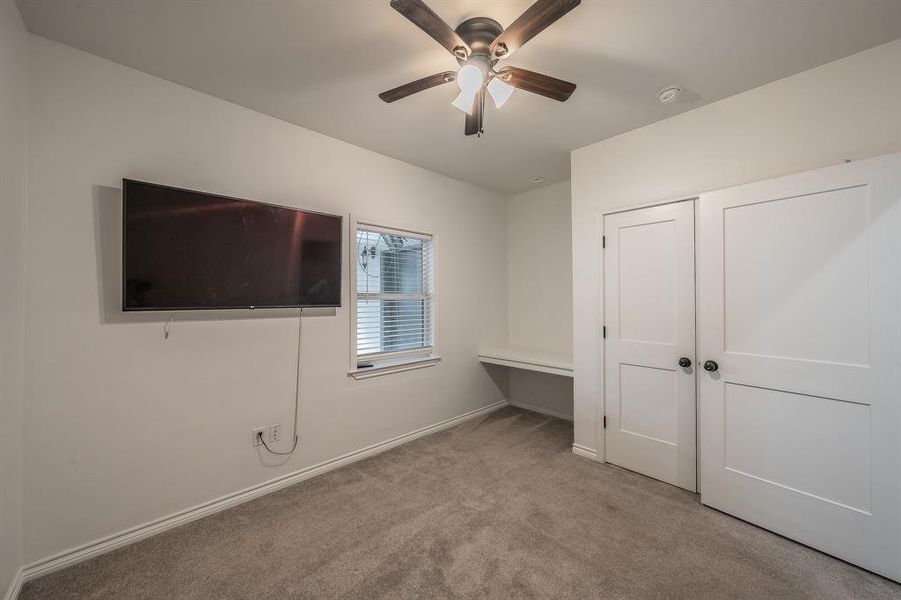 Unfurnished bedroom featuring carpet floors, an office area, and a ceiling fan Unfurnished bedroom featuring carpet floors, an office area, and a ceiling fan