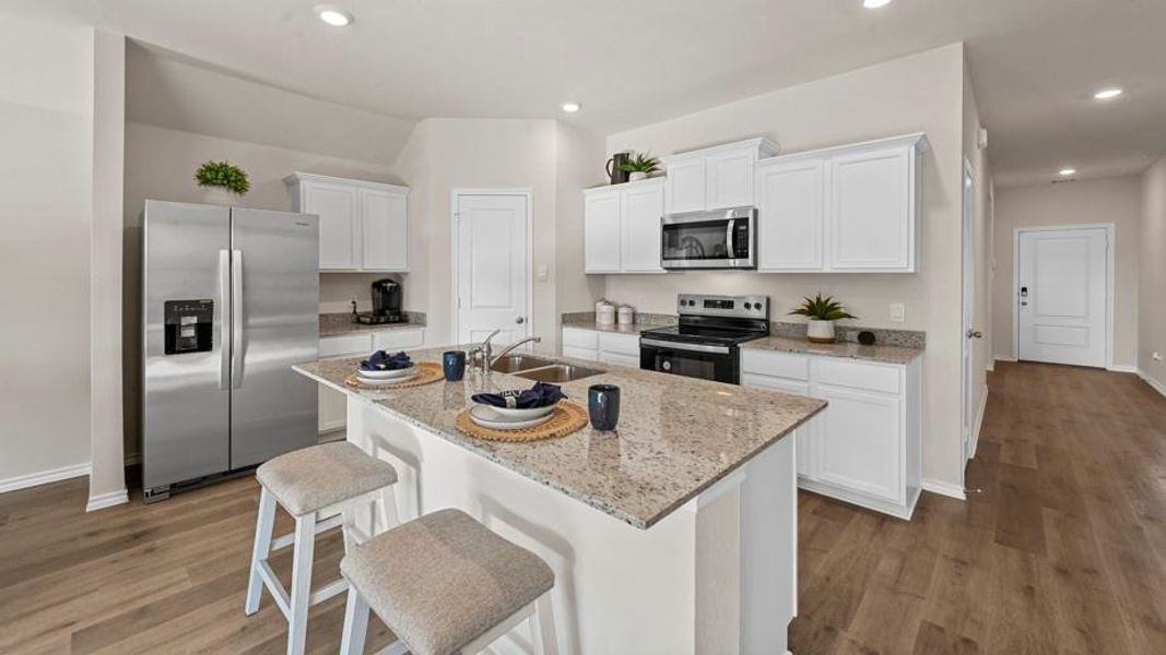 Kitchen featuring stainless steel appliances, white cabinetry, a breakfast bar, light wood finished floors, and recessed lighting