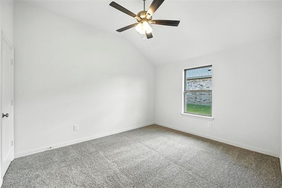 Spare room featuring vaulted ceiling, carpet, and ceiling fan