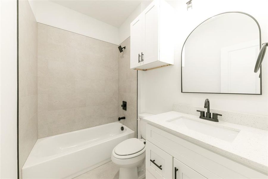 Full bathroom featuring toilet, tiled shower / bath, and vanity