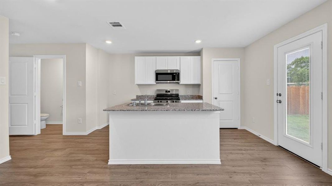 Kitchen island with a granite-style countertop and undermount sink