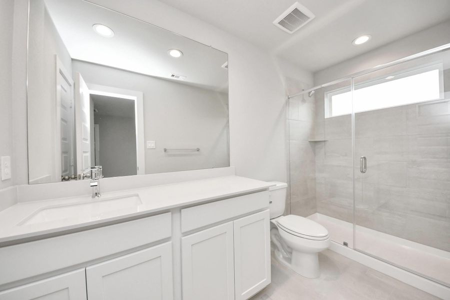 Secondary bath features tile flooring, a walk-in shower with tile surround, light stained wood cabinets, beautiful light countertop. Sample photo of completed home with similar floor plan. Actual colors and selections may vary. Secondary bath features tile flooring, a walk-in shower with tile surround, light stained wood cabinets, beautiful light countertop. Sample photo of completed home with similar floor plan. Actual colors and selections may vary.