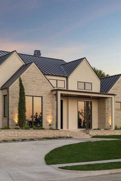 View of front facade with a standing seam roof, a metal roof, stone siding, stucco siding, and a yard View of front facade with a standing seam roof, a metal roof, stone siding, stucco siding, and a yard