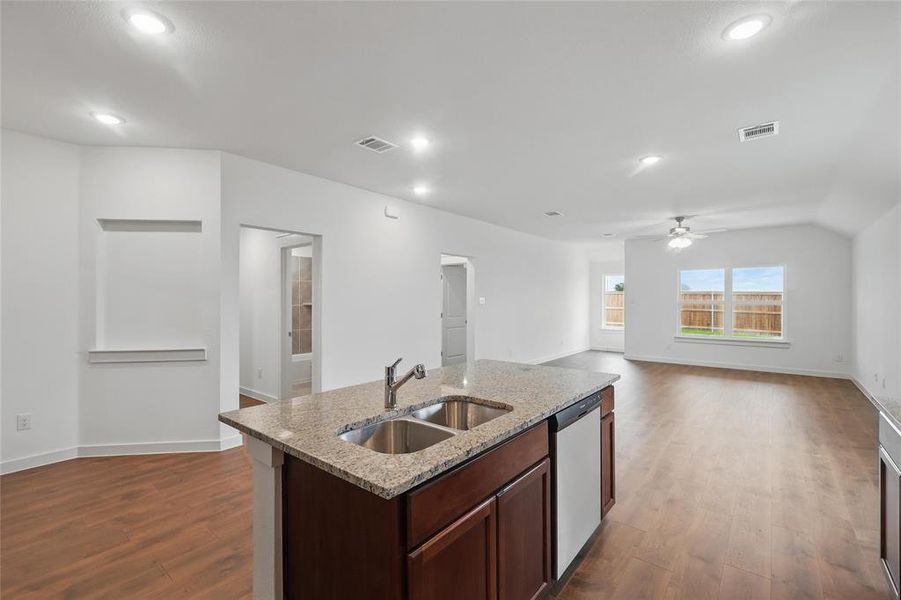 Kitchen featuring open floor plan, light stone counters, dark brown cabinetry, dark wood finished floors, and dishwasher Kitchen featuring open floor plan, light stone counters, dark brown cabinetry, dark wood finished floors, and dishwasher