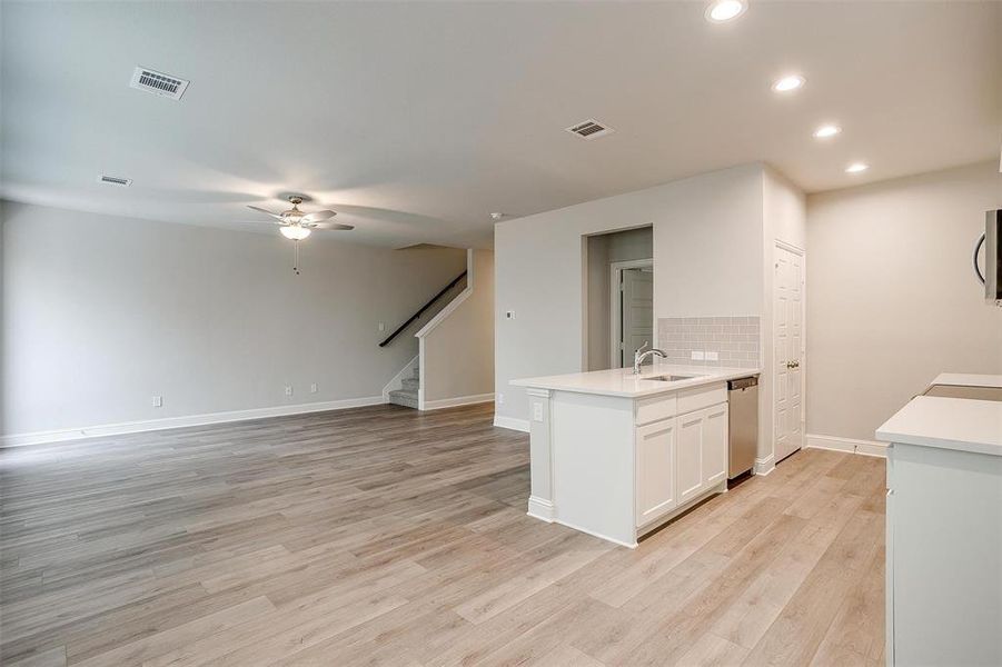 Kitchen with visible vents, backsplash, appliances with stainless steel finishes, light wood-style floors, and a sink