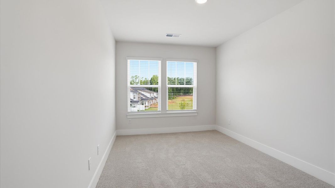 Notable bedroom offering soft carpet, a walk-in closet, and expansive windows overlooking the yard by DRB Homes Notable bedroom offering soft carpet, a walk-in closet, and expansive windows overlooking the yard by DRB Homes