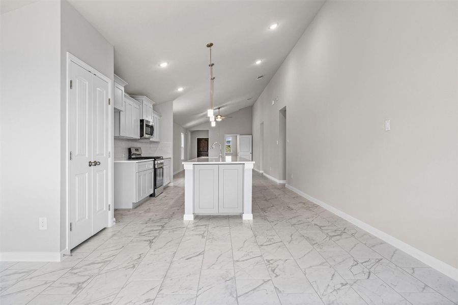 Soaring vaulted ceilings and marble-look tile floors frame this modern open kitchen design. Soaring vaulted ceilings and marble-look tile floors frame this modern open kitchen design.