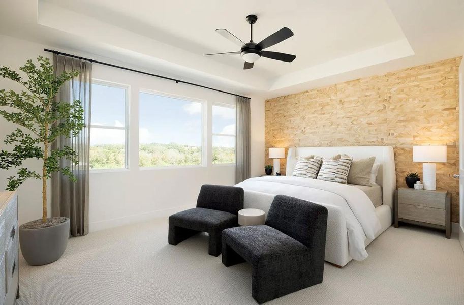 Carpeted bedroom featuring a tray ceiling, an accent wall, and a ceiling fan