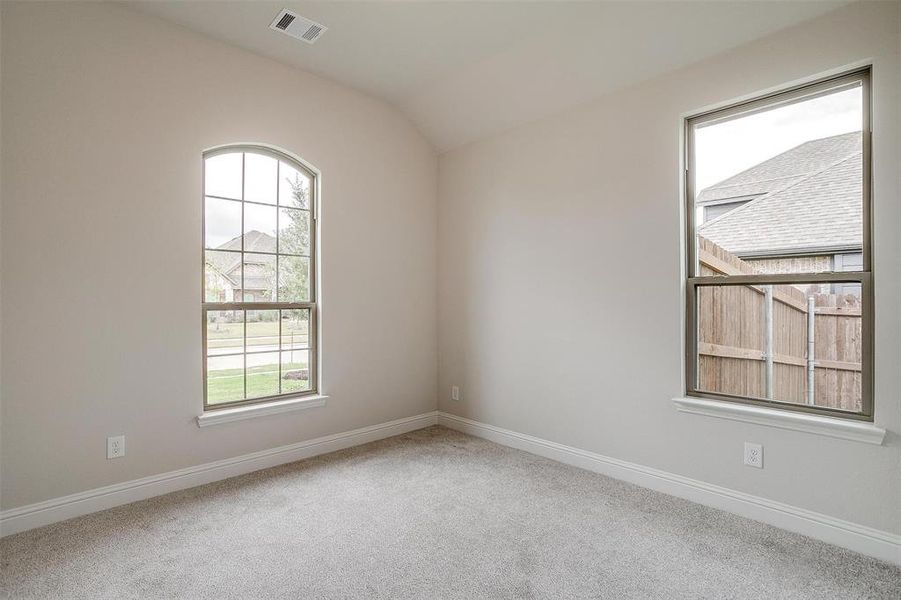 Empty room with vaulted ceiling and carpet