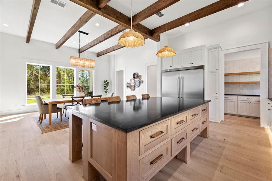 Kitchen with a kitchen island, decorative backsplash, light wood-style floors, hanging light fixtures, and beam ceiling