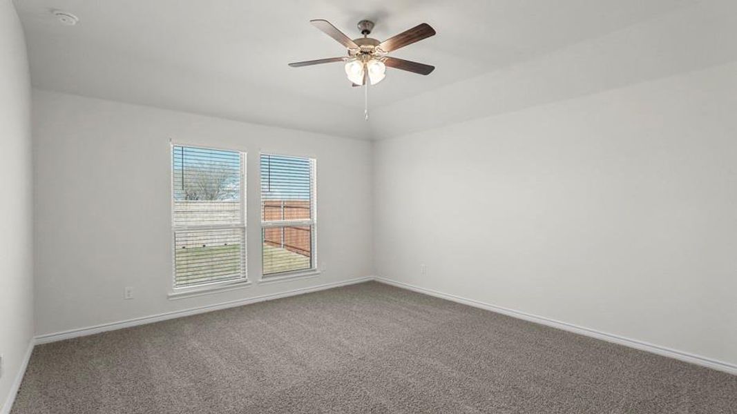 Bright interior room featuring neutral colored carpet, white walls, and two windows with blinds