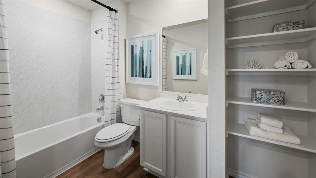 Full bathroom with shower / bathtub combination with curtain, vanity, and dark wood finished floors Full bathroom with shower / bathtub combination with curtain, vanity, and dark wood finished floors