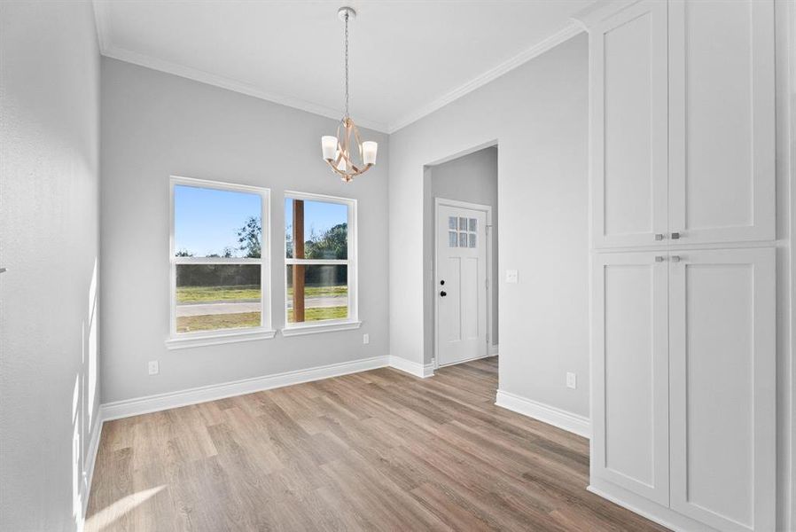 Unfurnished dining area featuring crown molding, a chandelier, and light wood-style floors