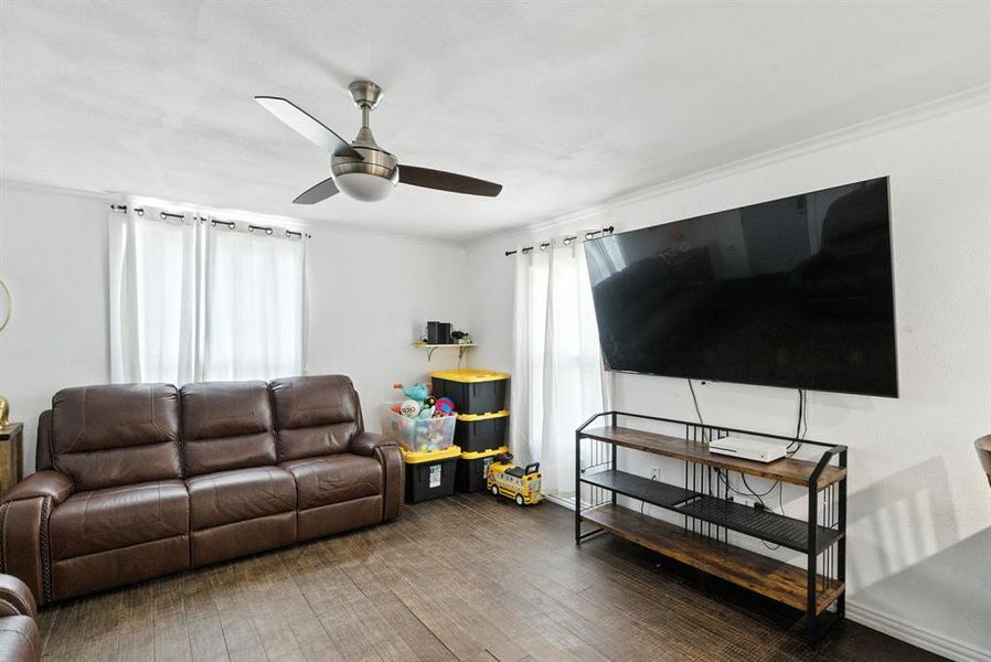 Living area with wood finished floors, ceiling fan, and ornamental molding