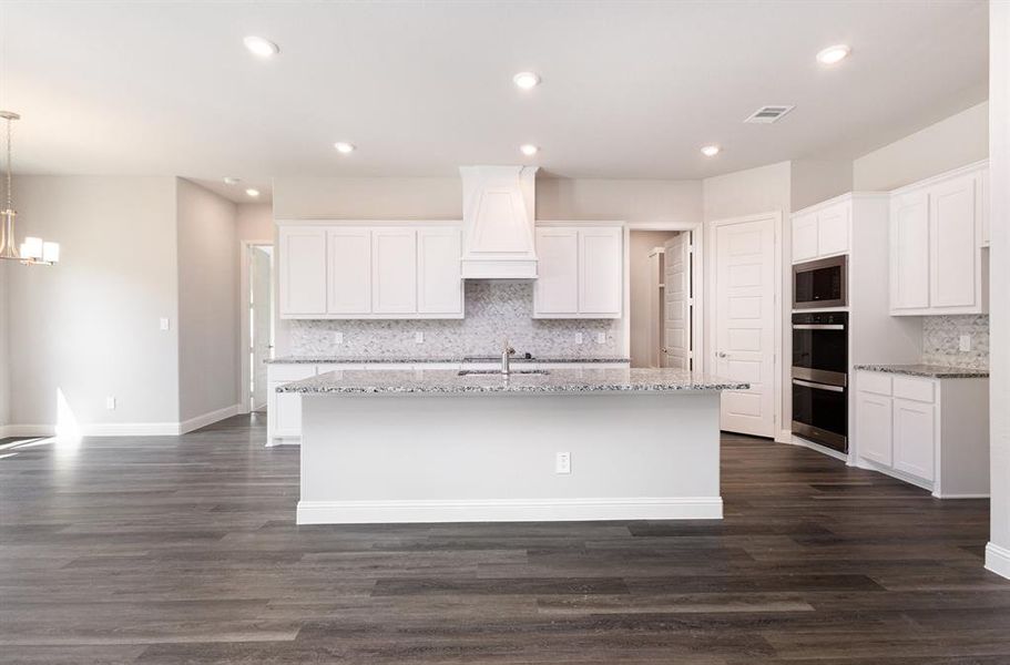 Kitchen featuring light stone countertops, backsplash, white cabinets, dark wood-type flooring, and recessed lighting Kitchen featuring light stone countertops, backsplash, white cabinets, dark wood-type flooring, and recessed lighting