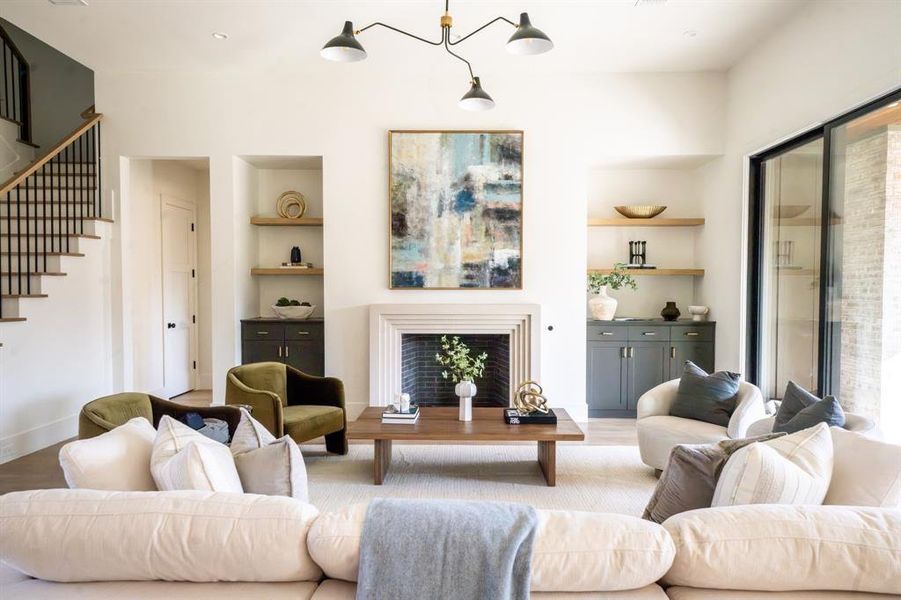 Living room with built in features, an inviting chandelier, and light wood-type flooring