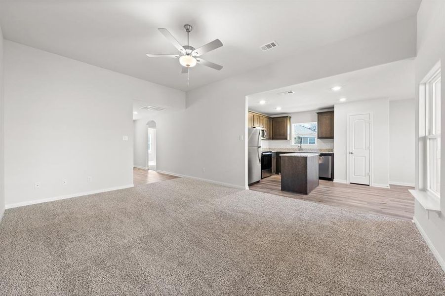 Unfurnished living room with sink, ceiling fan, and light colored carpet