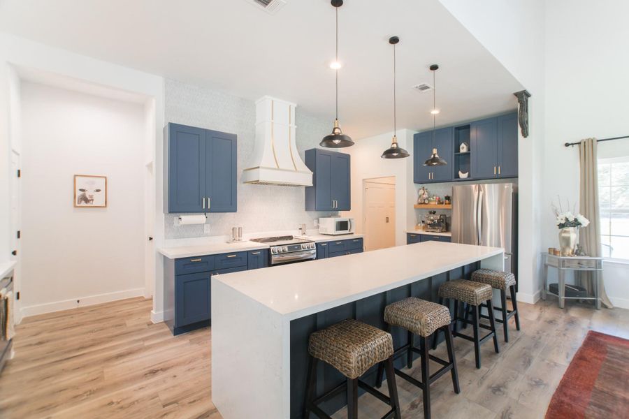 The central island/breakfast bar is beautifully accented by three sleek and modern pendant lights. The central island/breakfast bar is beautifully accented by three sleek and modern pendant lights.