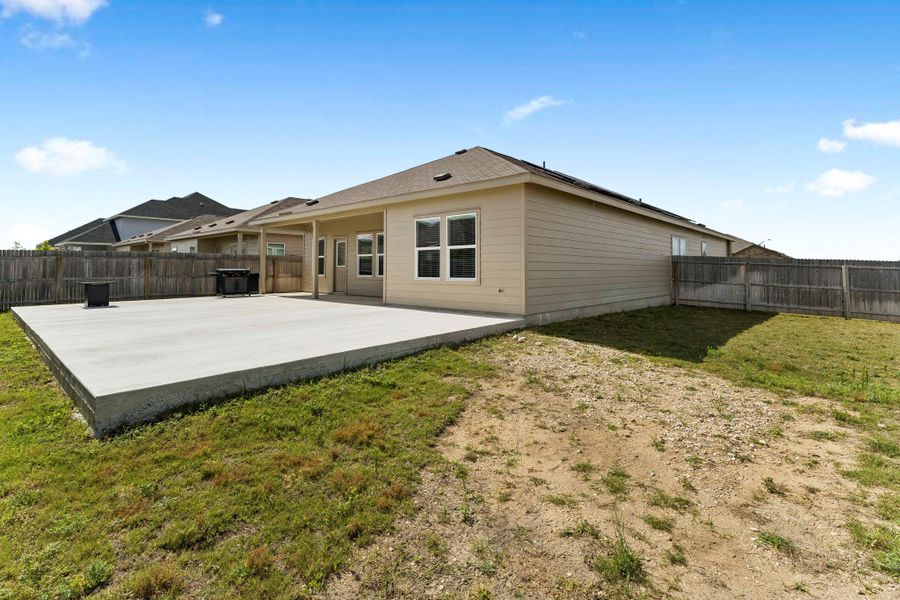 A spacious backyard with a generous concrete patio offers abundant space for outdoor activities and relaxation.