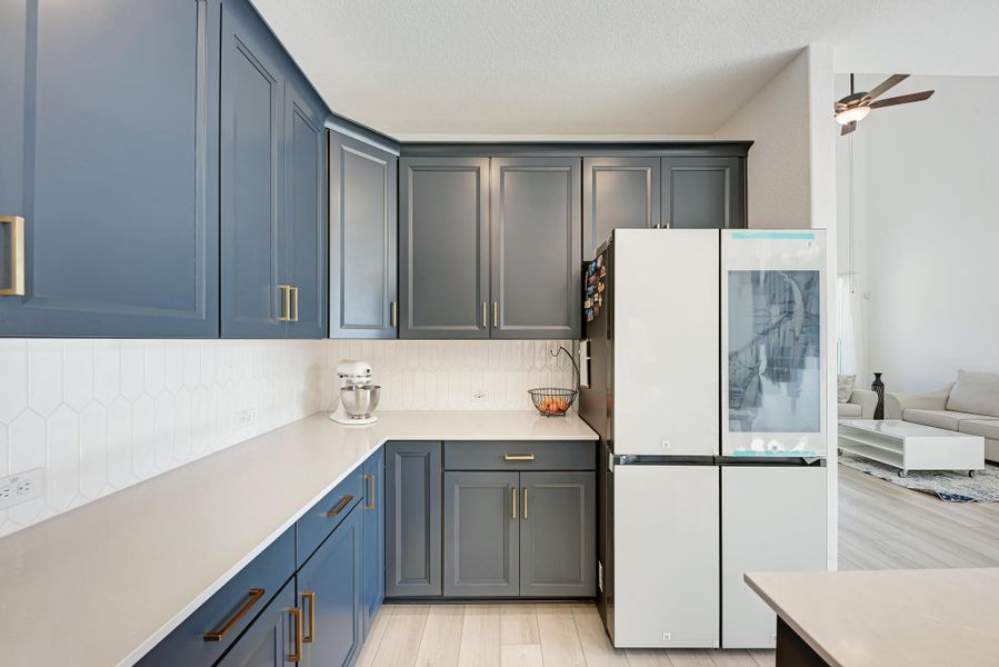Kitchen featuring smart refrigerator, light wood-style floors, tasteful backsplash, open floor plan, and light stone countertops