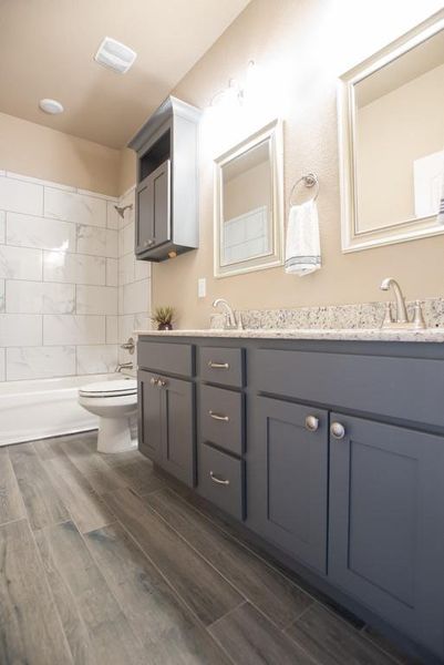 Bathroom with double vanity, wood finish floors, and shower combination Bathroom with double vanity, wood finish floors, and shower combination