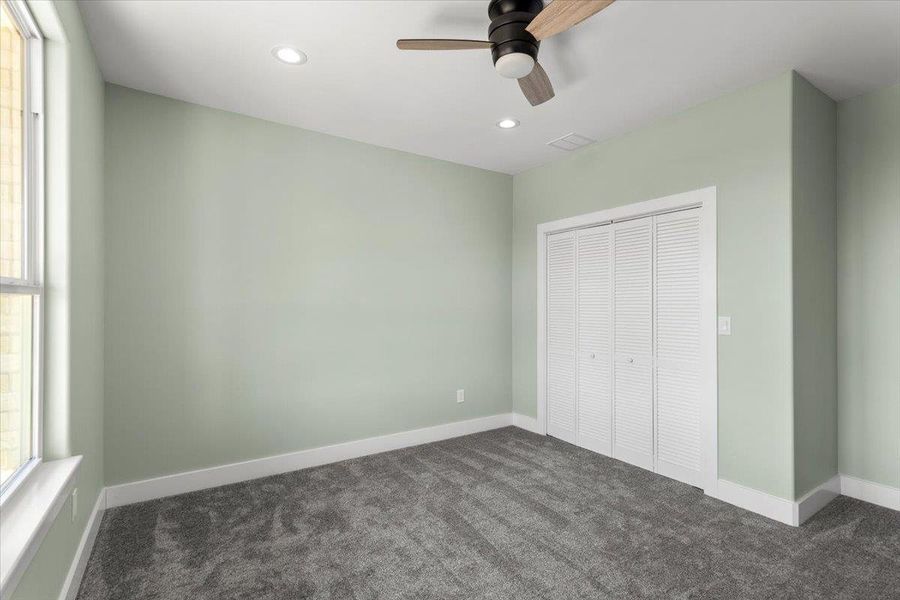 Bedroom number 1 featuring dark carpet, recessed lighting, a closet, ceiling fan, and multiple windows