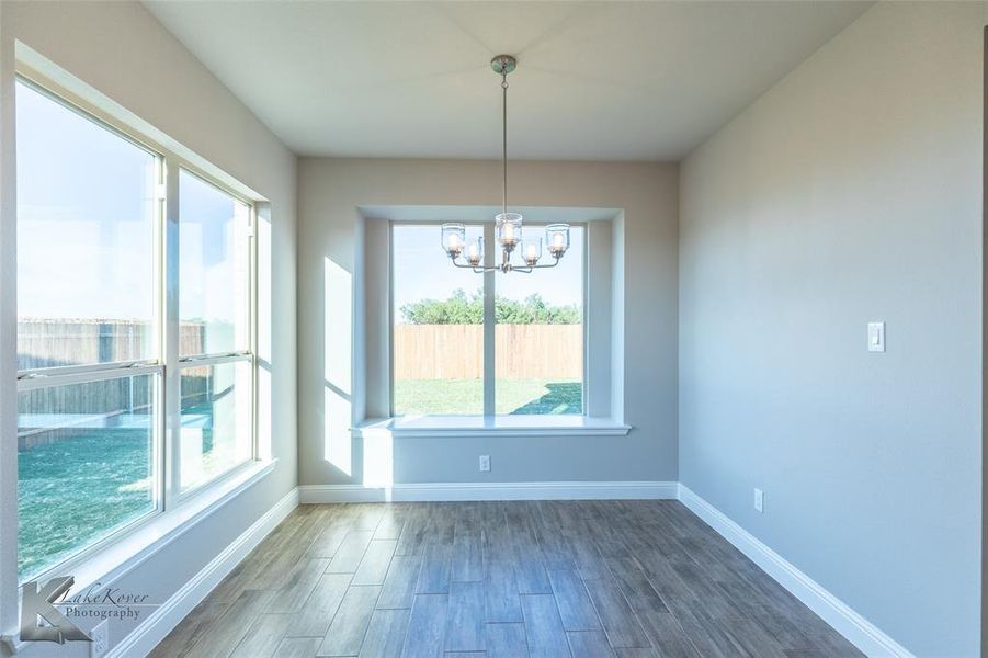 Unfurnished dining area featuring dark wood-type flooring and a chandelier