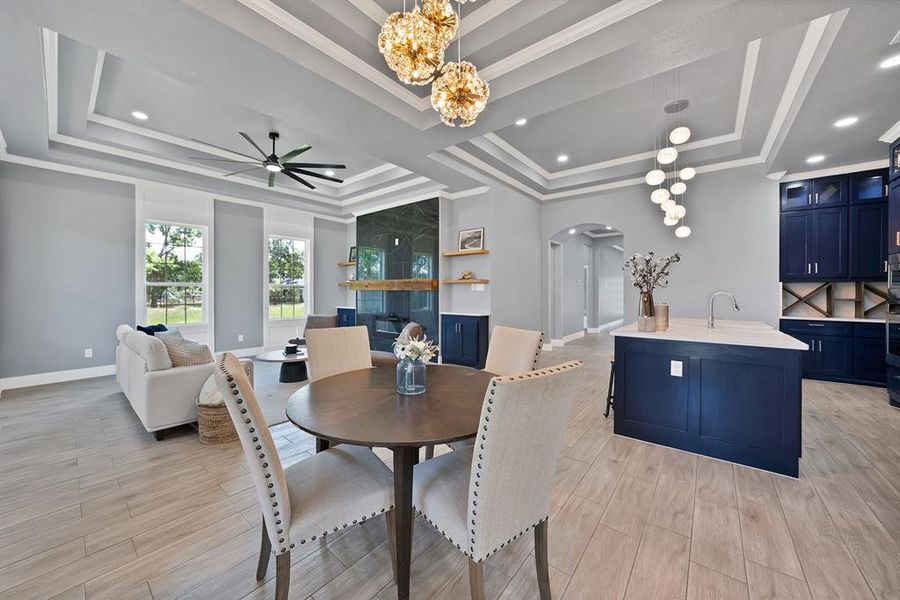 Open-concept living space featuring wood-finish flooring, tray ceilings with recessed lighting, and a modern kitchen island with a white countertop