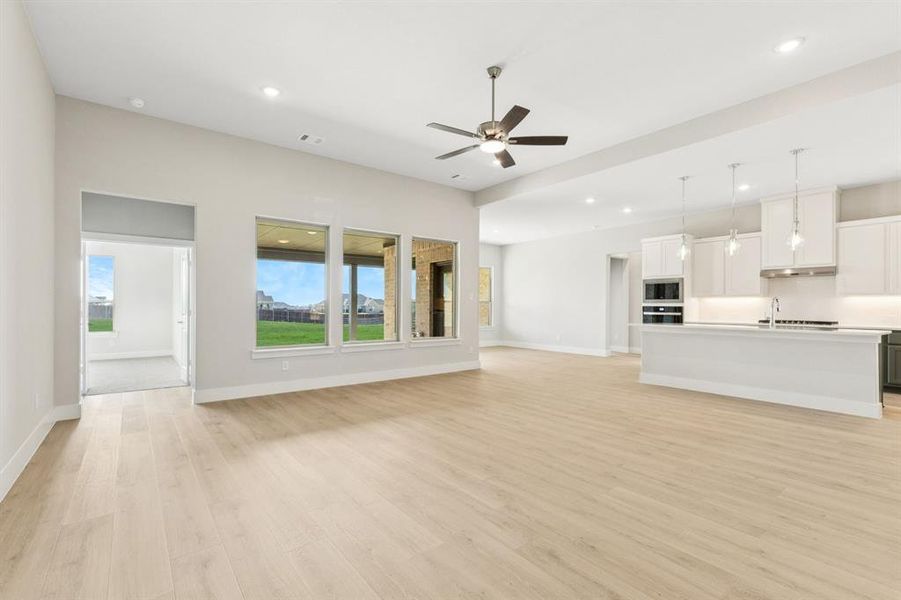 Kitchen with white cabinetry, wall oven, pendant lighting, a center island with sink, and stainless steel microwave Kitchen with white cabinetry, wall oven, pendant lighting, a center island with sink, and stainless steel microwave