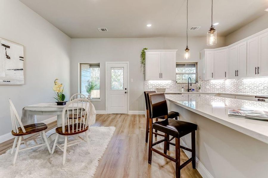 Kitchen featuring backsplash, white cabinets, a healthy amount of sunlight, and light hardwood / wood-style floors