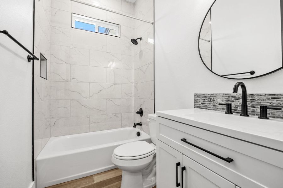 Full bath with vanity,  shower combination, light wood-style floors, and backsplash