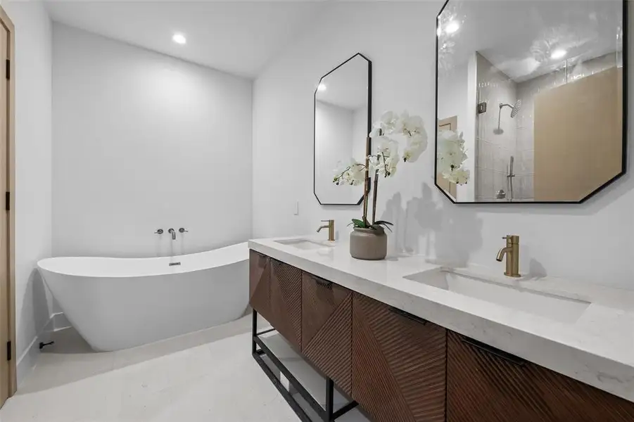 Full bathroom with a freestanding tub, double vanity, a tile shower, light tile patterned floors, and recessed lighting